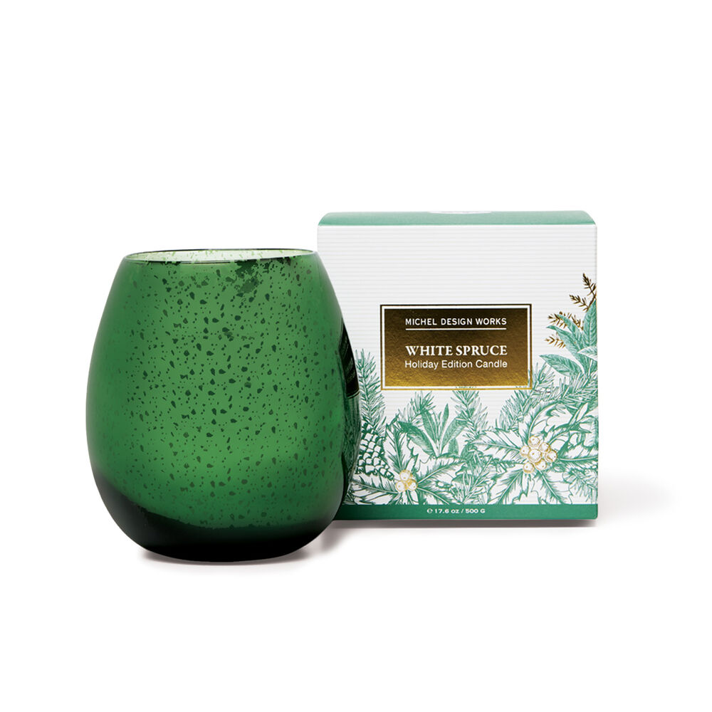 A green speckled glass candle jar standing next to its white and green floral box labeled 'White Spruce Holiday Edition Candle' by Michel Design Works, on a white background.