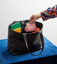 Black handbag with colorful items on a blue surface