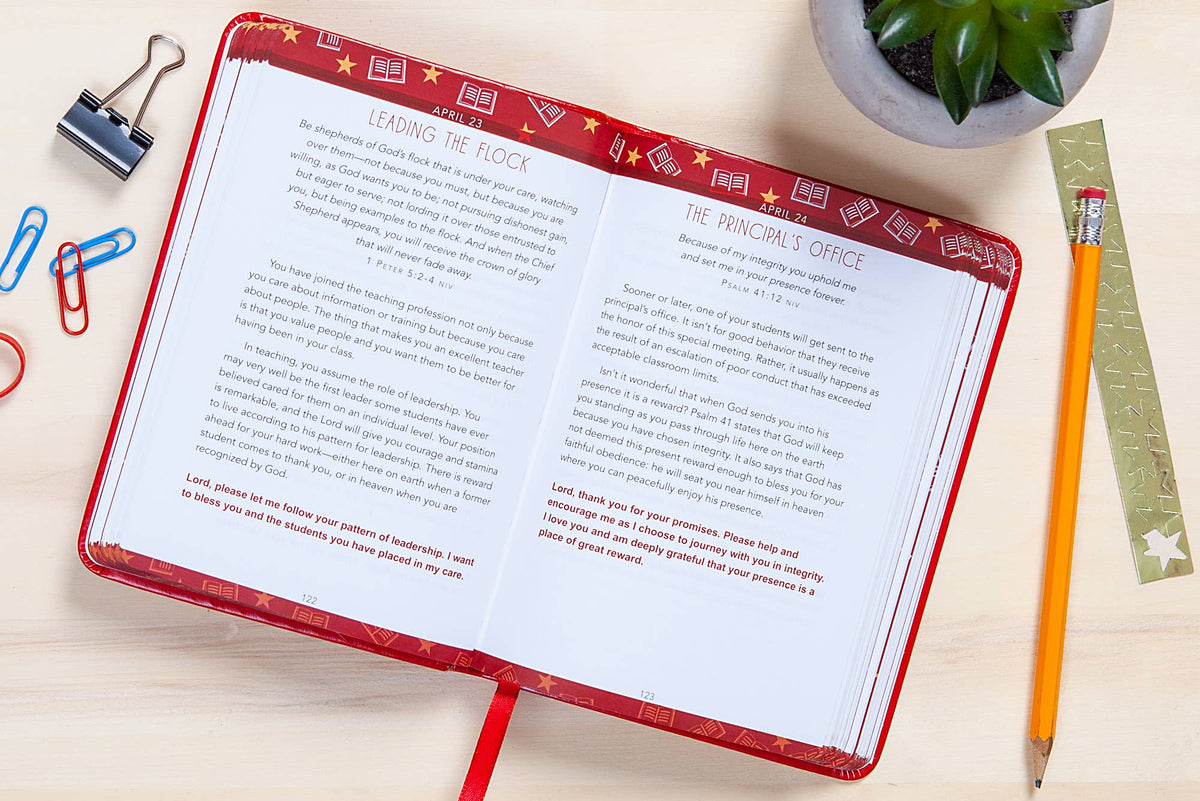 Open book with red binding on a desk with stationery items