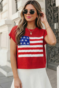 Woman wearing a red sweater with an American flag design outdoors.