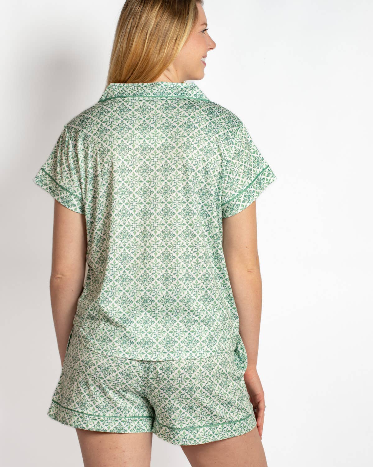 Woman wearing a green patterned pajama set on a plain background