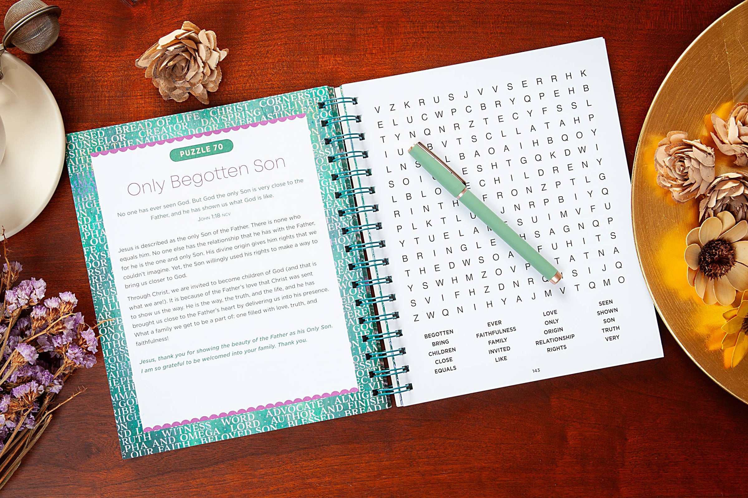 Open spiral-bound book with a word search and text on a wooden surface with decorative elements.