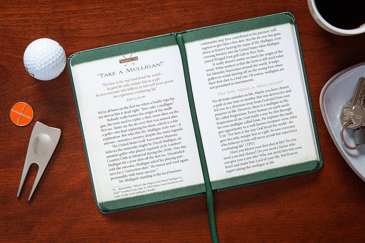 Open book on a wooden surface with golf accessories and a cup of coffee.