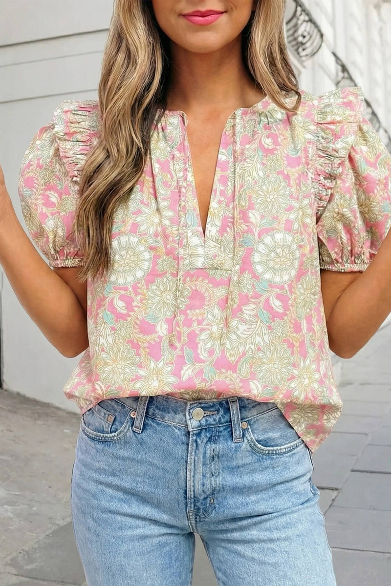 Woman wearing a floral blouse and jeans against a neutral background