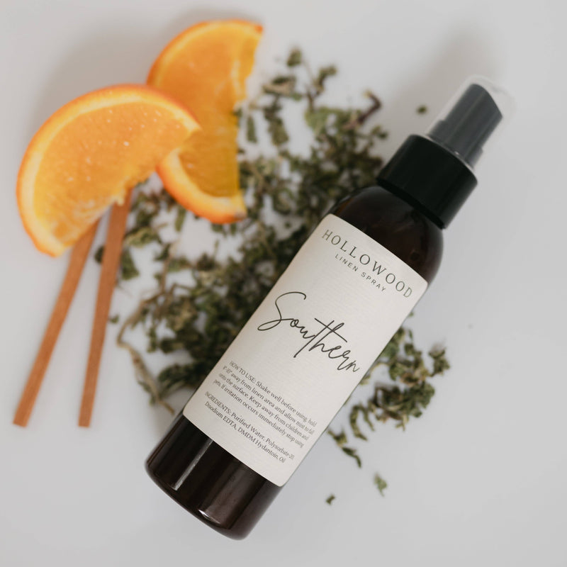 Hollywood Linen Spray bottle with oranges and herbs on a light background