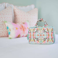 Floral patterned toiletry bag on a bed with pillows in the background