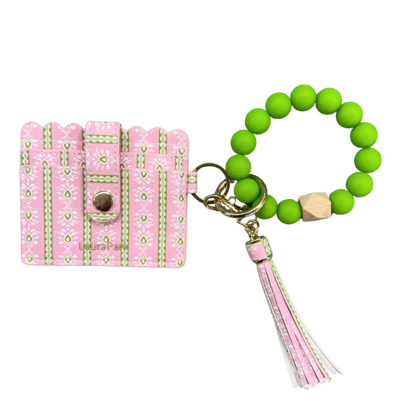 Pink keychain with decorative elements and green beaded bracelet with tassel on a white background