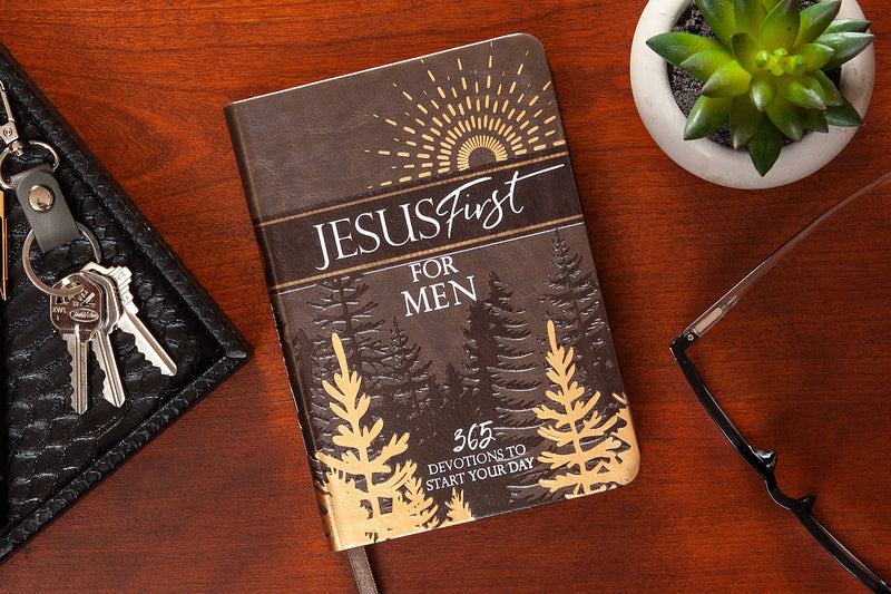 Journal titled 'Jesus First for Men' on a wooden surface with keys, glasses, and a plant.