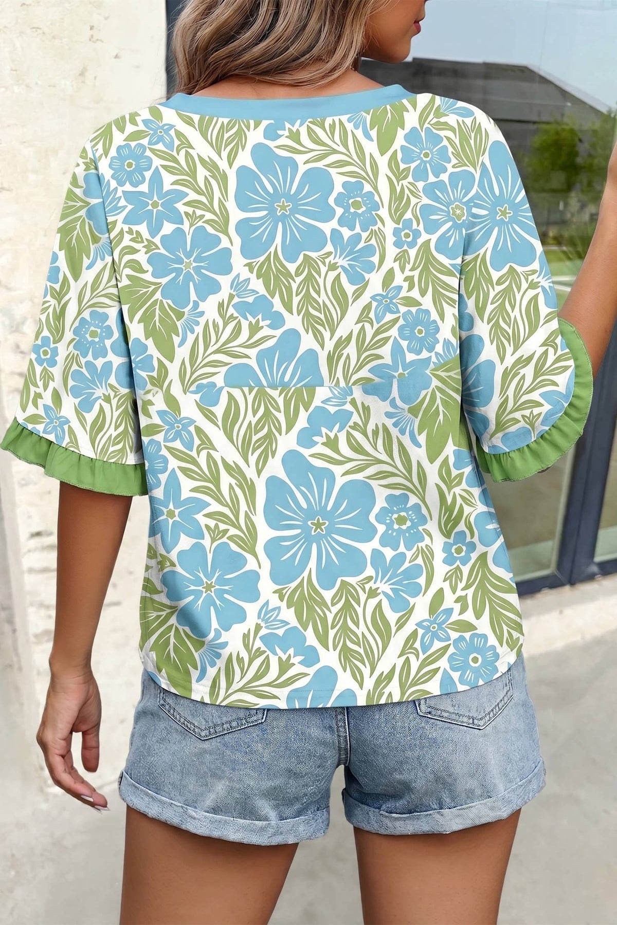 Person wearing a floral patterned shirt with blue and green flowers.