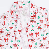 A close-up of a holiday-themed pajama top with a white base, red and green Christmas print, and red piping along the collar and front placket.
