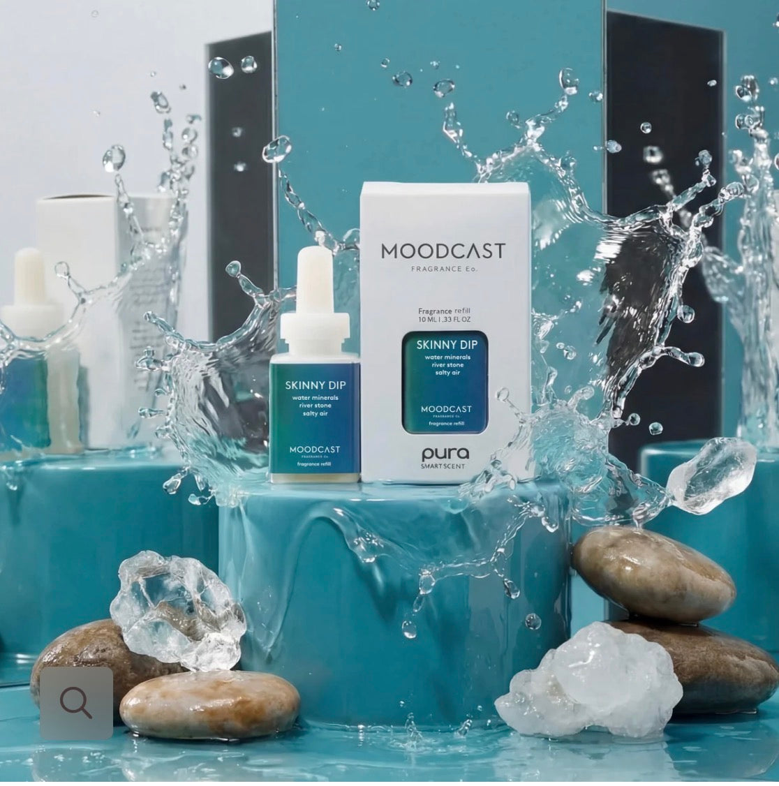 Moodcast Skinnit Dip skincare product shown with its white box and blue dropper bottle, styled with water splashes, ice, and smooth stones on a turquoise set.