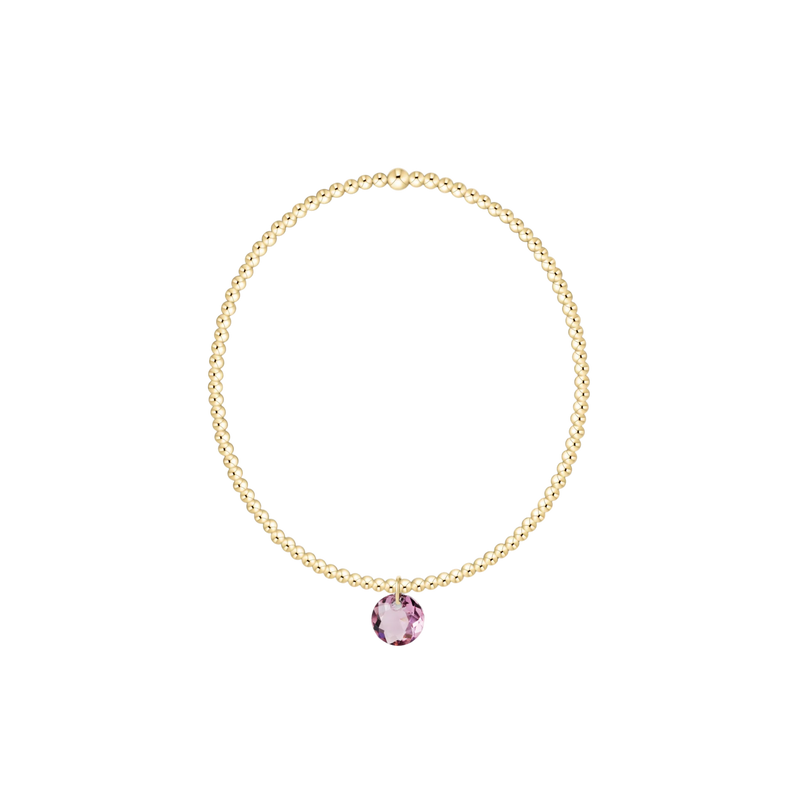 Gold necklace with a pink gemstone on a white background