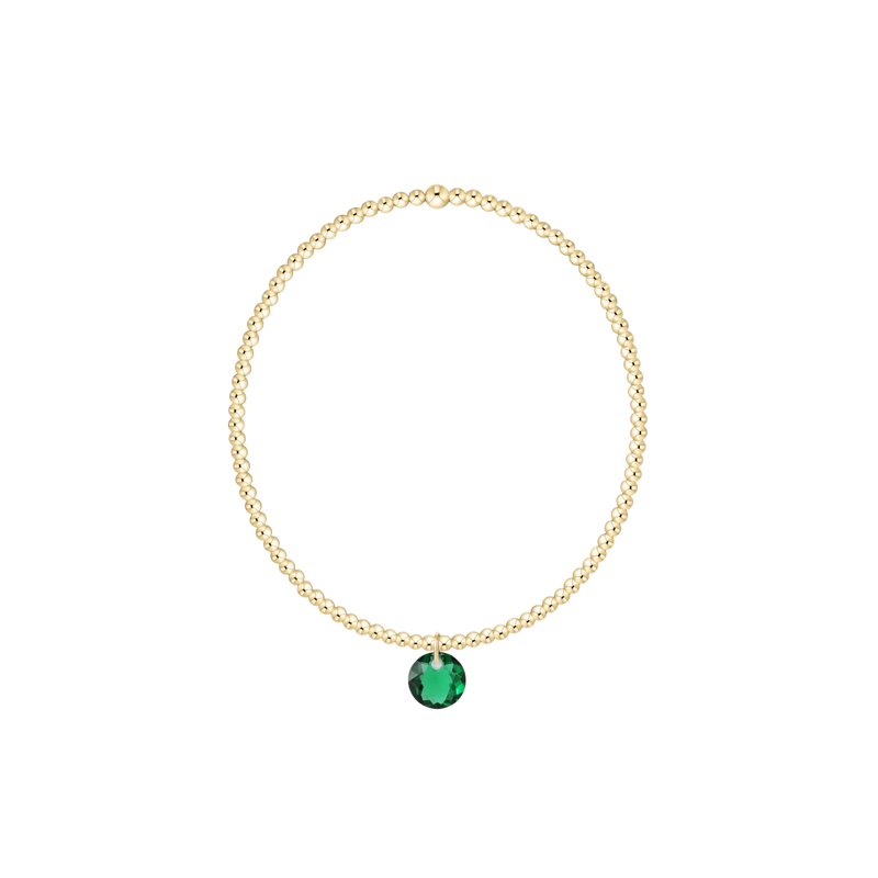 Gold necklace with a green gemstone on a white background