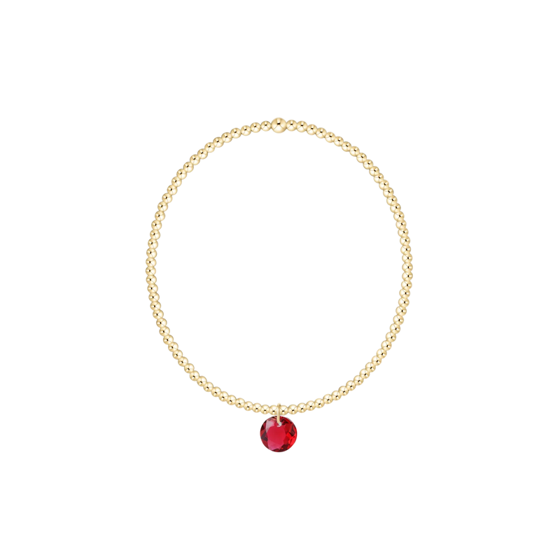 Gold bracelet with a red gemstone on a white background