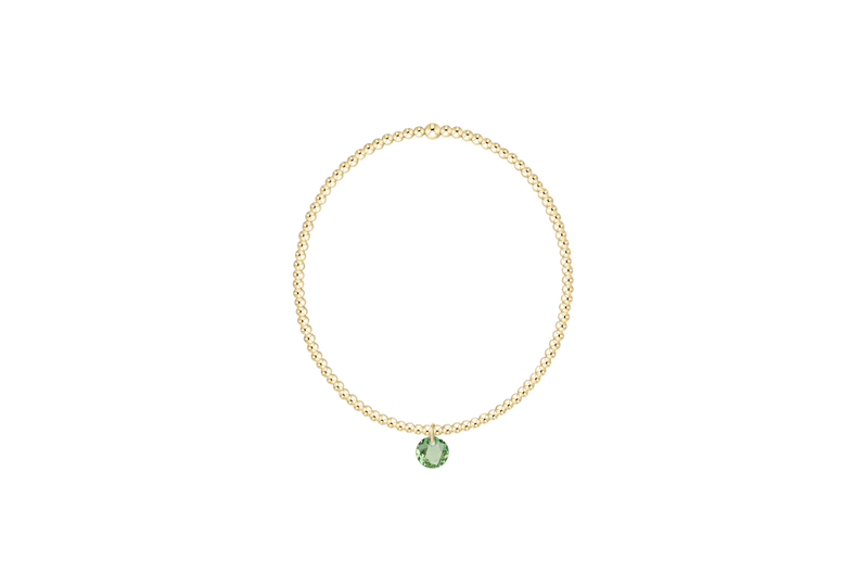 Gold bracelet with a green gemstone on a white background
