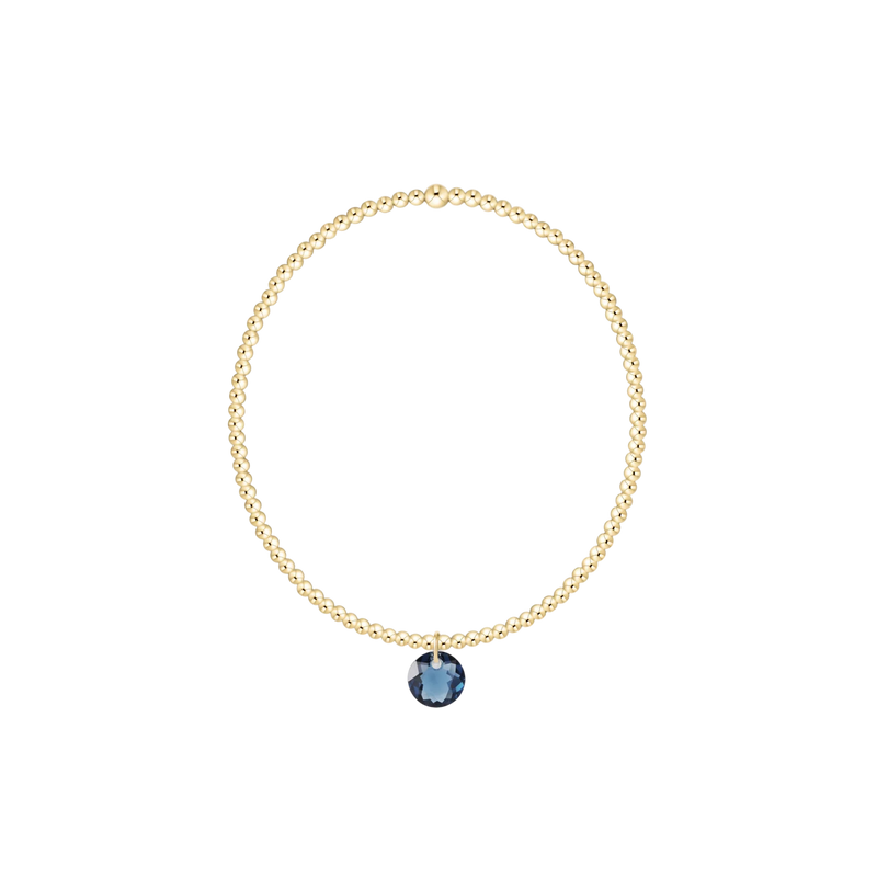 Gold necklace with a blue gemstone pendant on a white background