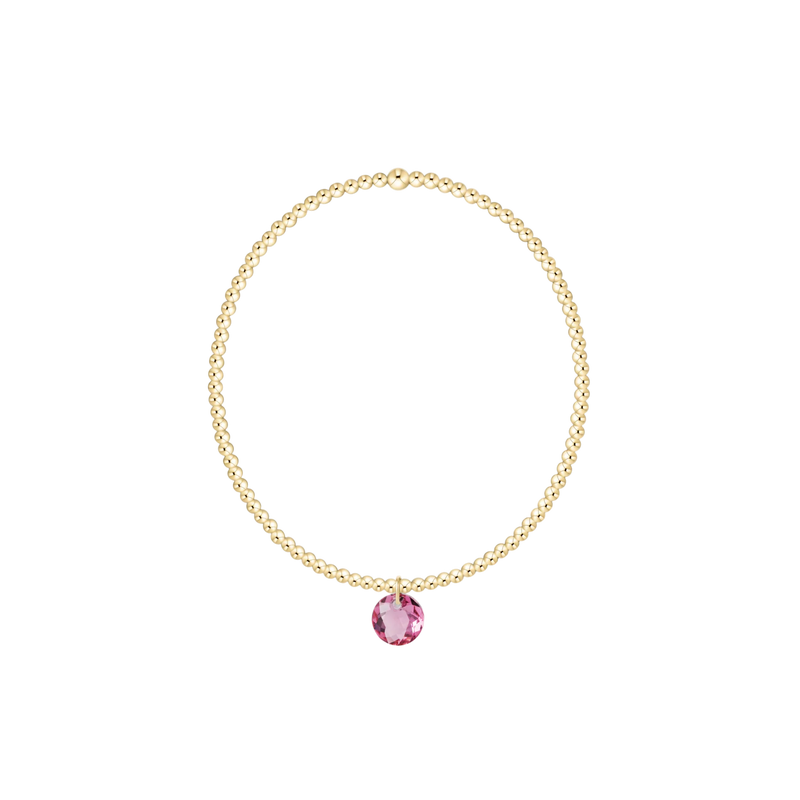 Gold necklace with a pink gemstone on a white background