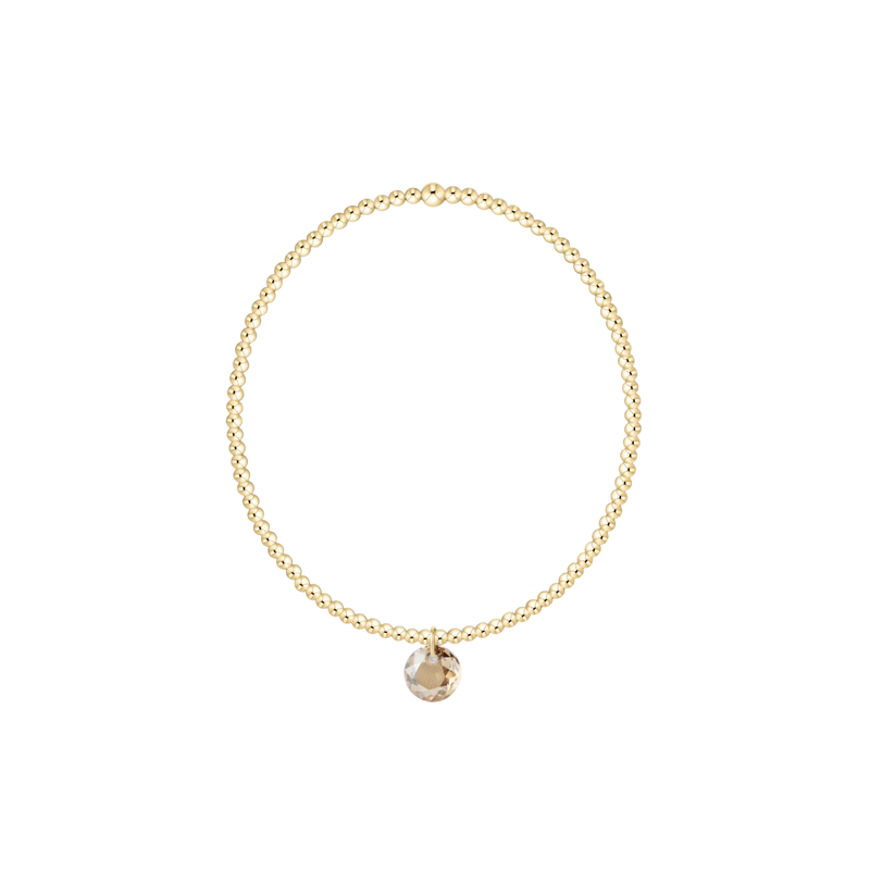 Gold bracelet with a small round pendant on a white background