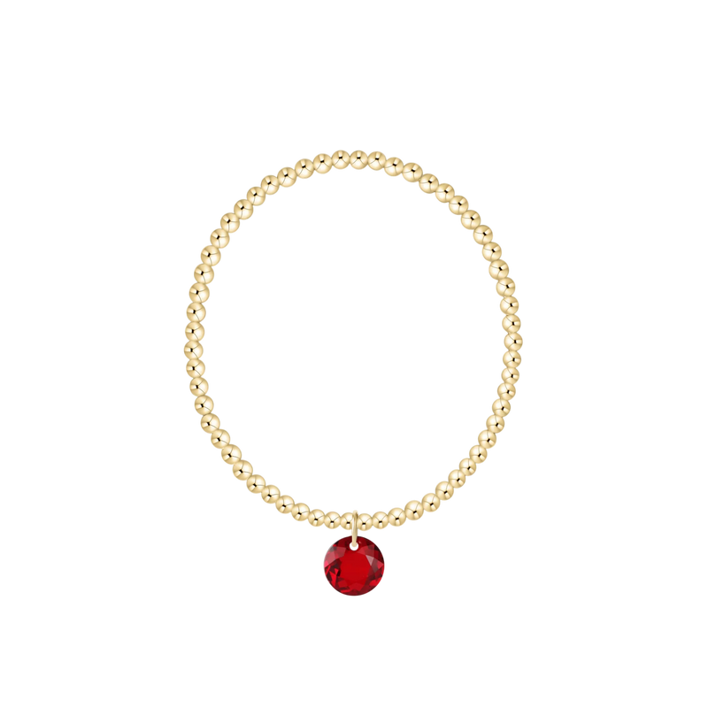 Gold beaded bracelet with red gemstone charm
