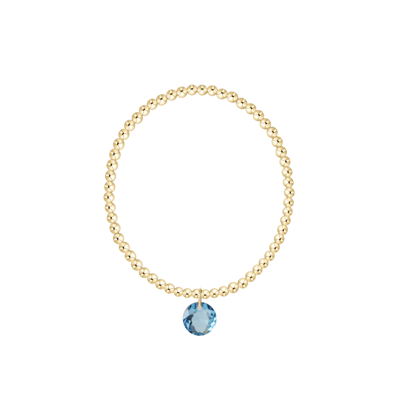 Gold bracelet with a blue gemstone on a white background