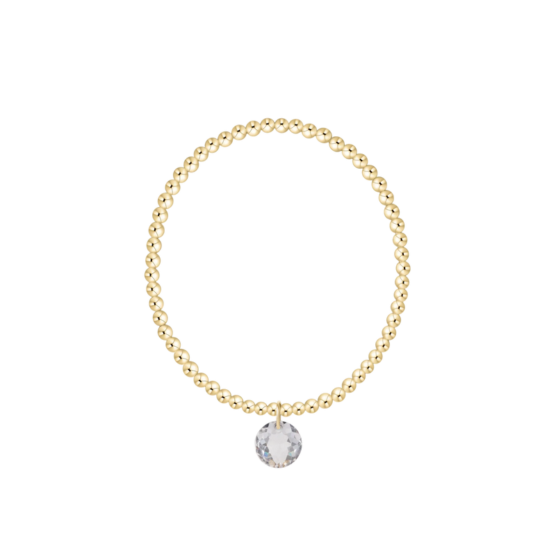 Gold beaded bracelet with a clear crystal charm on a white background
