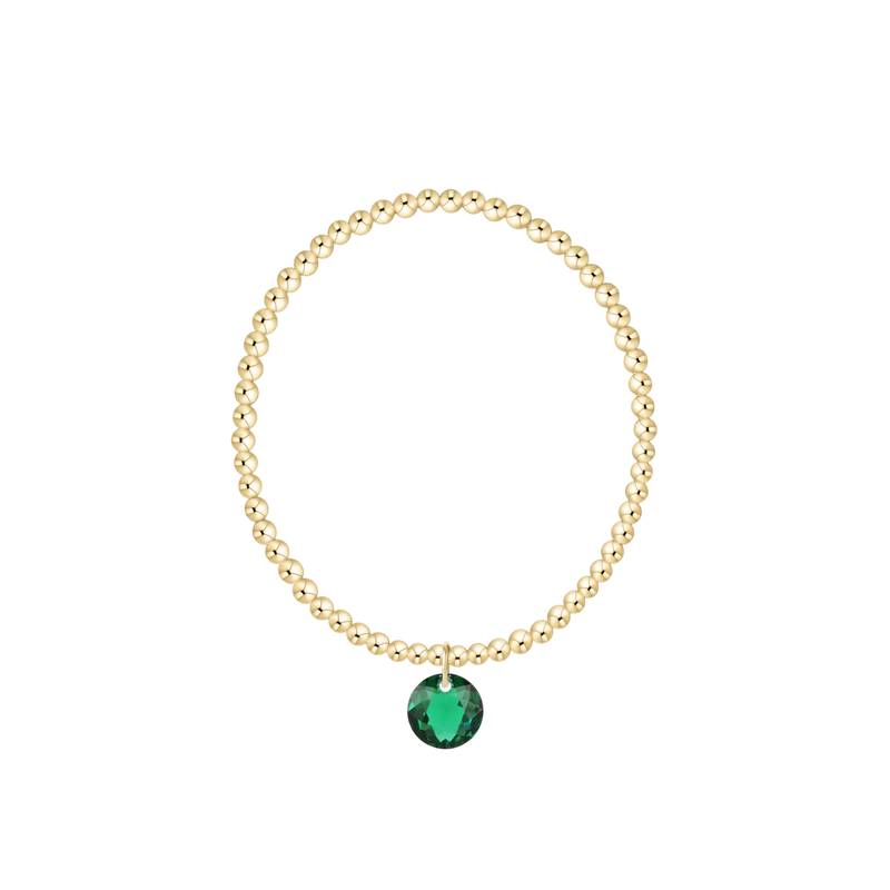 Gold bracelet with a green gemstone on a white background