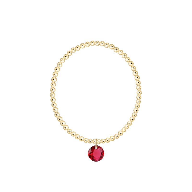 Gold bracelet with a red gemstone on a white background