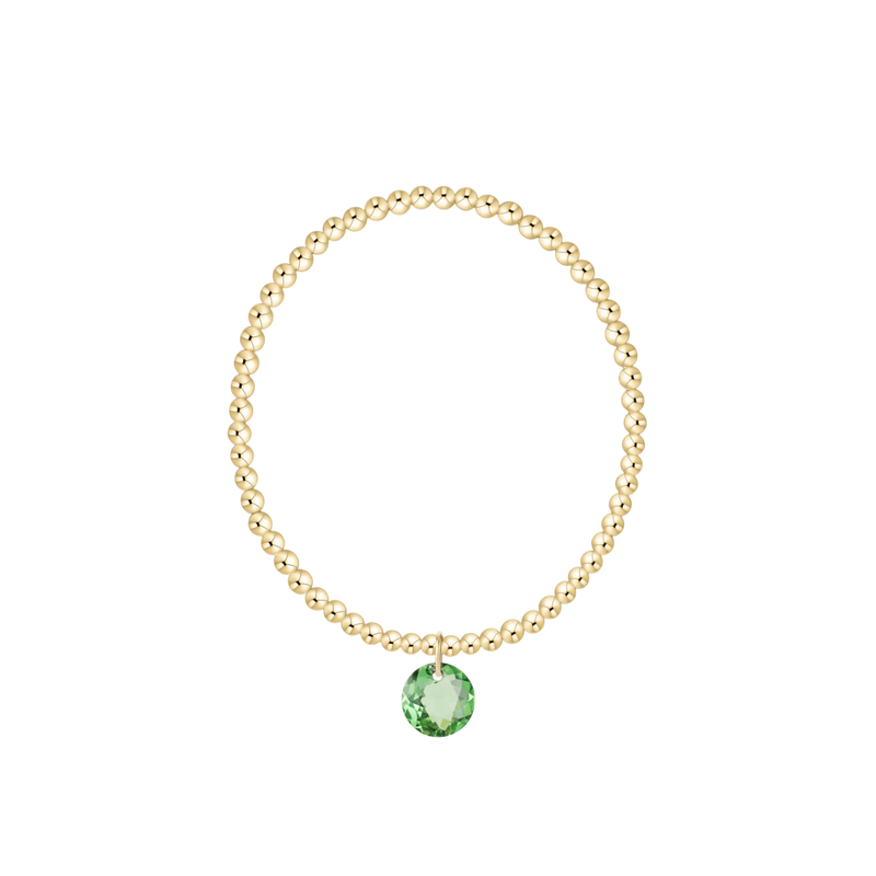 Gold bracelet with a green gemstone on a white background