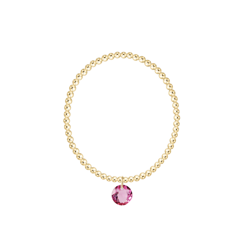 Gold bracelet with a pink gemstone on a white background