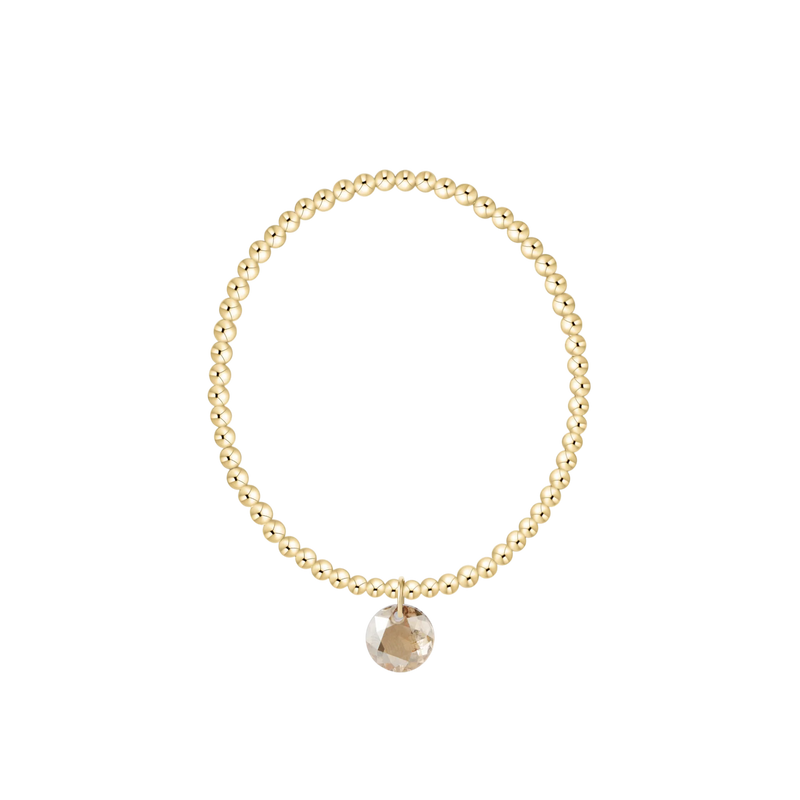 Gold beaded bracelet with a round pendant on a white background