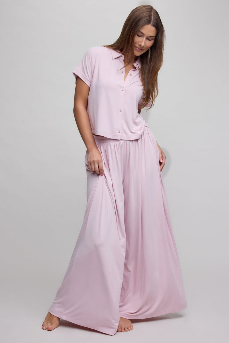 Woman wearing a pink pajama set on a plain background
