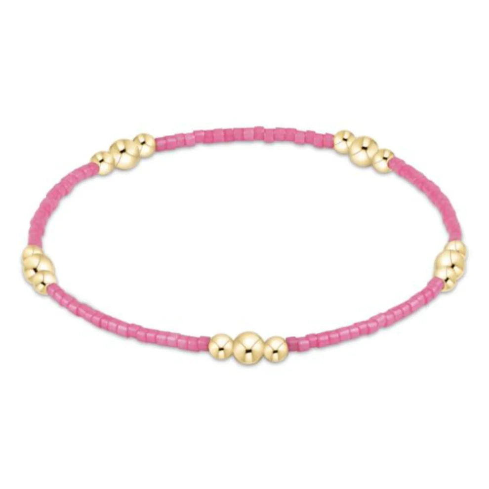 Pink beaded bracelet with gold beads on a white background