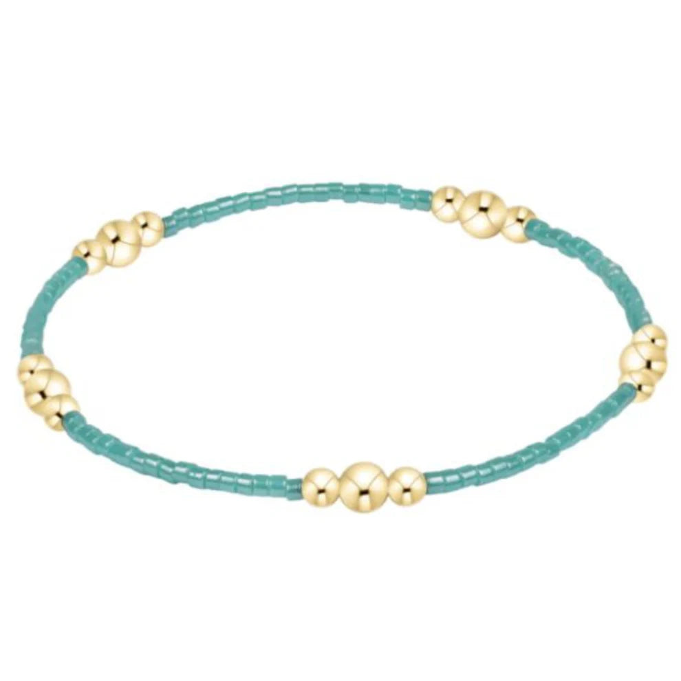 Bracelet with gold beads on a turquoise string against a white background