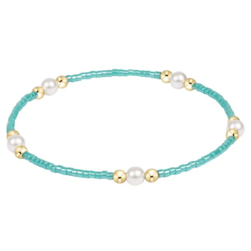 Turquoise beaded bracelet with pearls and gold accents on a white background