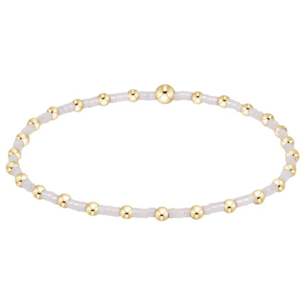 Bracelet with gold and white beads on a white background