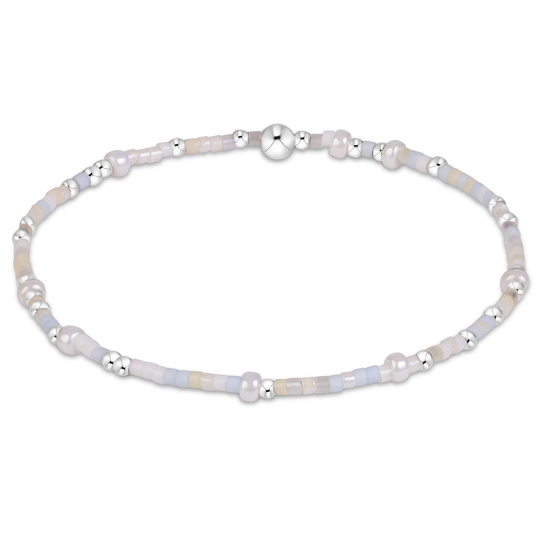 A delicate beaded bracelet with iridescent pale blue, lavender, and white beads, accented by small silver spacer beads and a polished silver clasp, shown on a plain white background.
