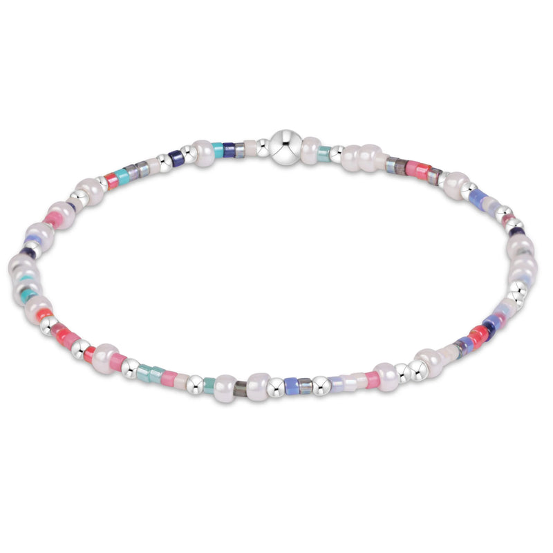 A beaded stretch bracelet featuring white freshwater pearls, silver spacer beads, and small colorful accent beads in pink, blue, and green, displayed on a clean white background.