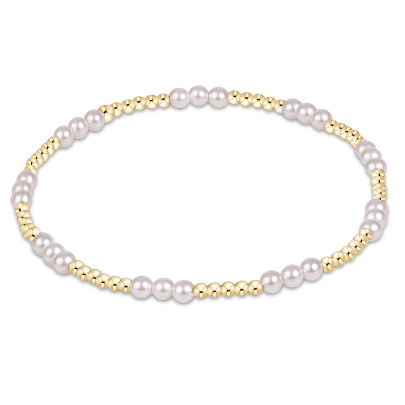 A beaded stretch bracelet featuring large white pearls and small polished gold beads, arranged in a circular shape on a clean white background.