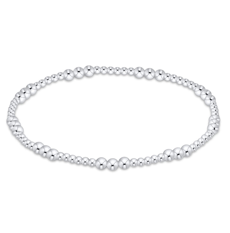 A silver beaded stretch bracelet with alternating small and larger polished round beads, displayed on a clean white background.