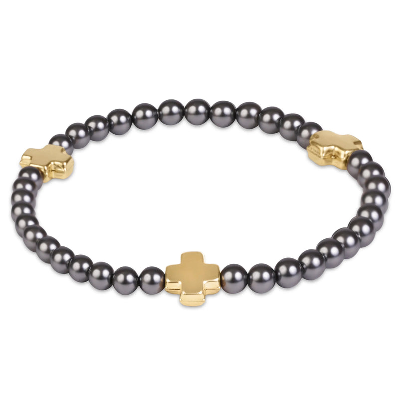A beaded bracelet featuring dark gray pearls and polished gold-tone cross-shaped charms, displayed on a clean white background.