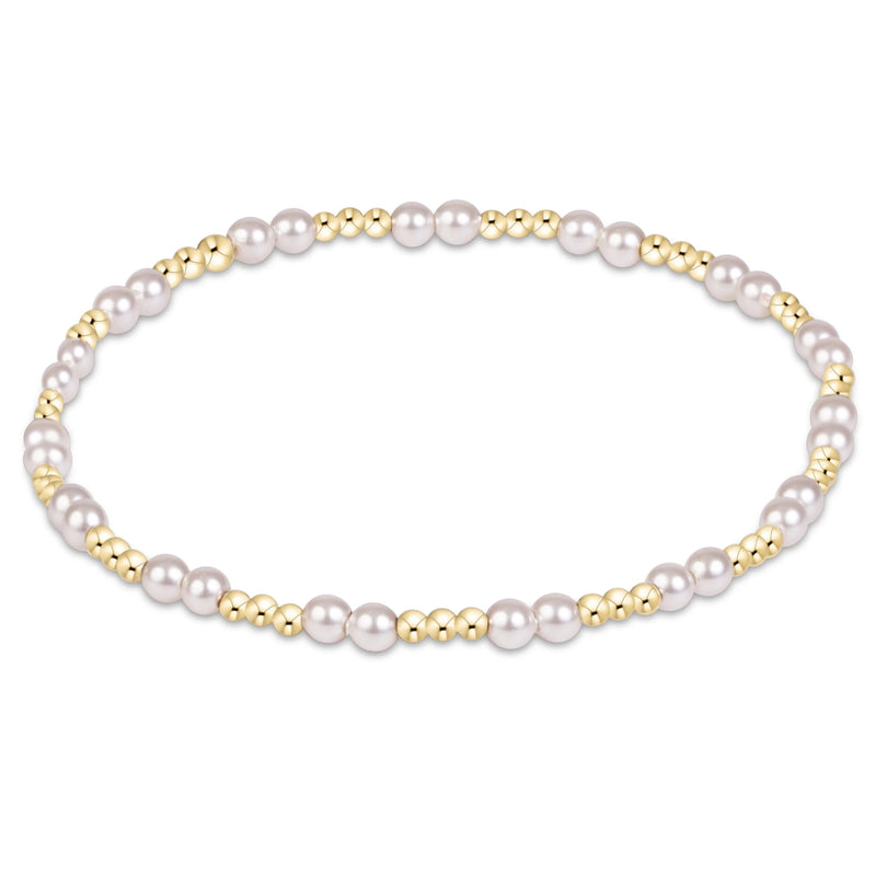 A beaded stretch bracelet featuring large white pearls and small polished gold spacer beads, arranged in a circular shape on a solid white background.