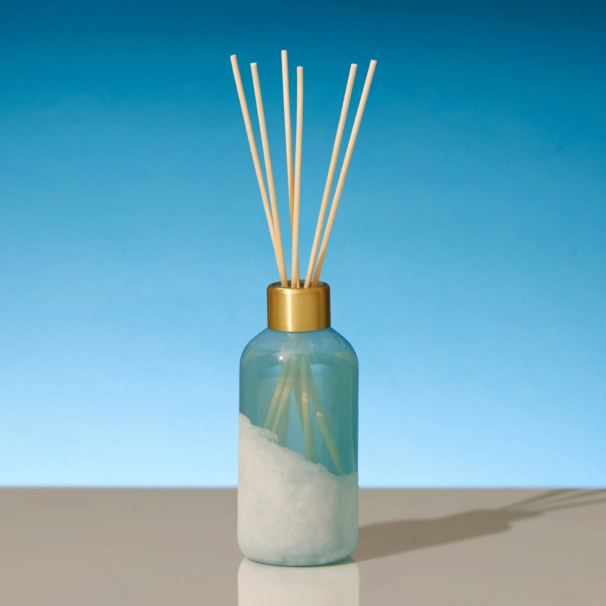 Diffuser bottle with wooden sticks on a blue background