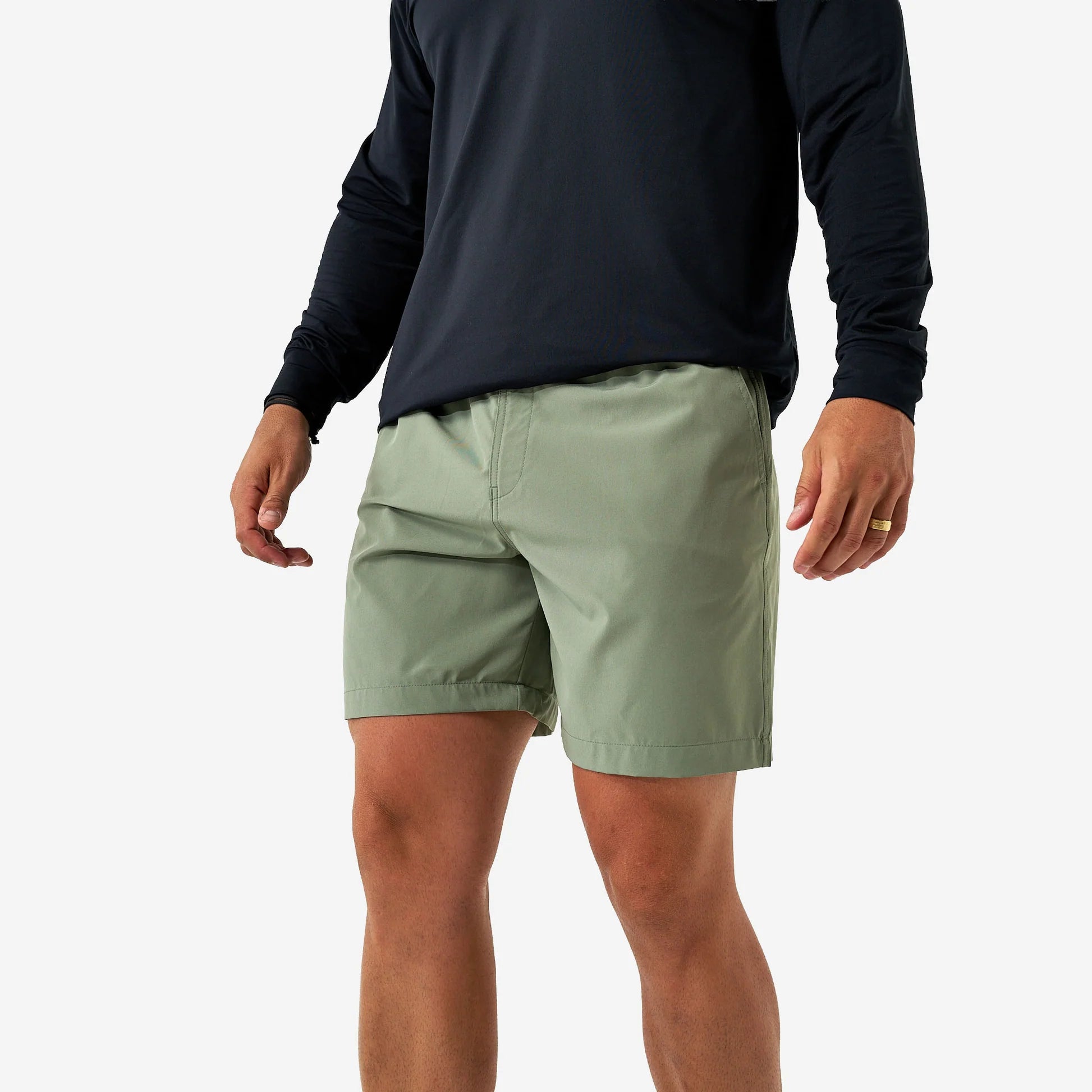 Person wearing green shorts and a black long-sleeve shirt on a white background