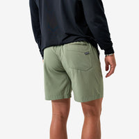 Person wearing green shorts and a black long-sleeve shirt on a white background