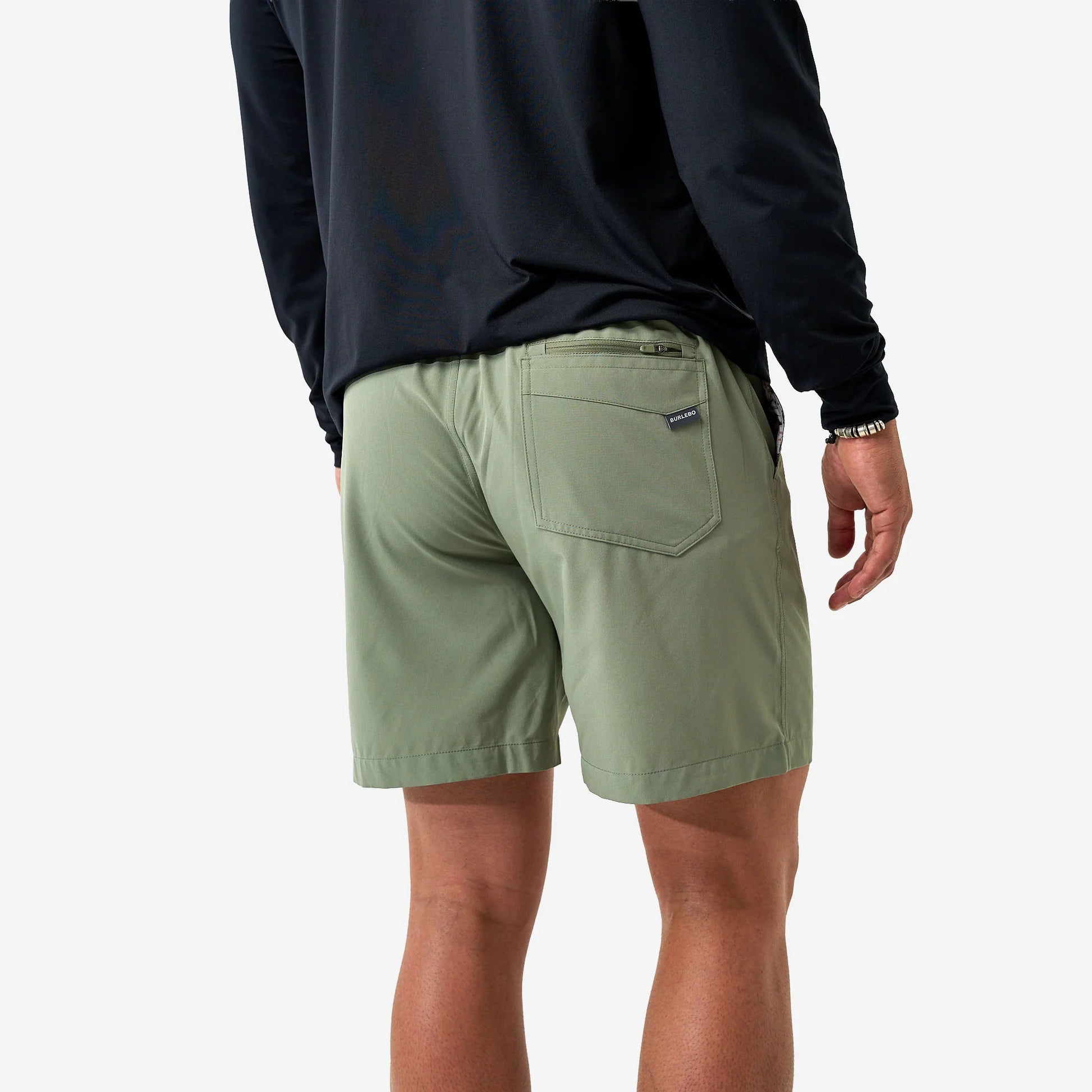 Person wearing green shorts and a black long-sleeve shirt on a white background