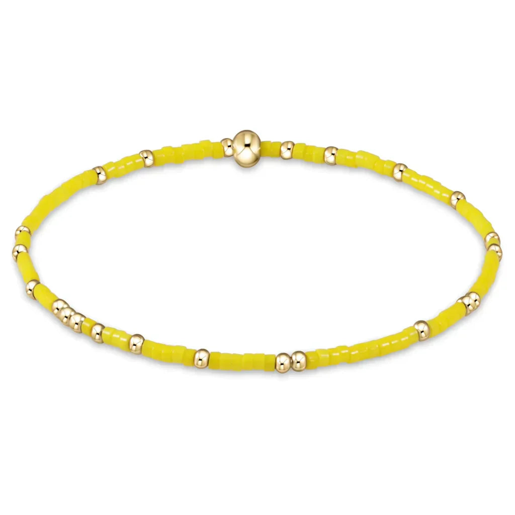 Yellow beaded bracelet with gold accents on a white background