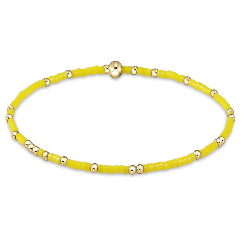 Yellow beaded bracelet with gold accents on a white background