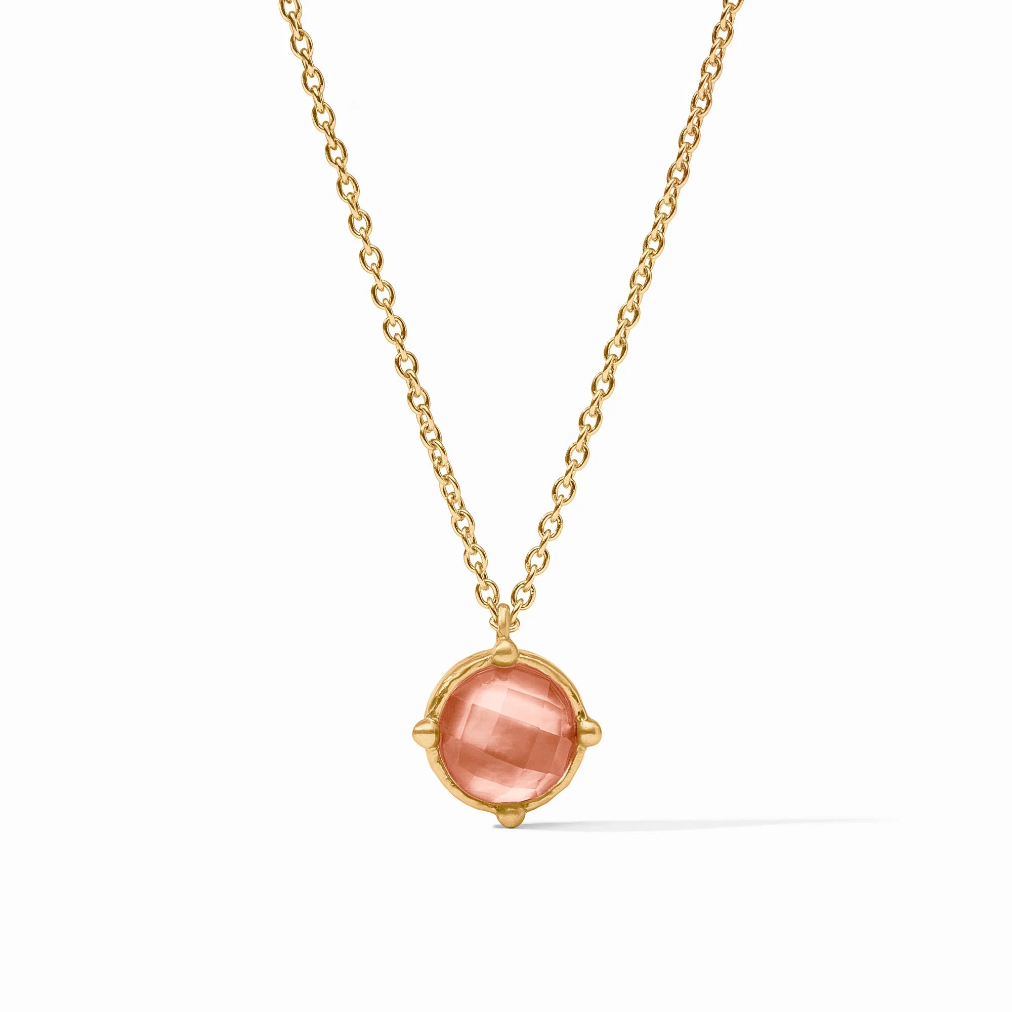 Gold necklace with a pink gemstone pendant on a white background