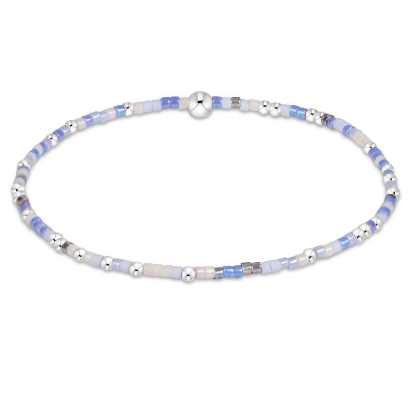 A delicate beaded bracelet with light blue, white, and silver beads, featuring a polished silver clasp, displayed on a clean white background.