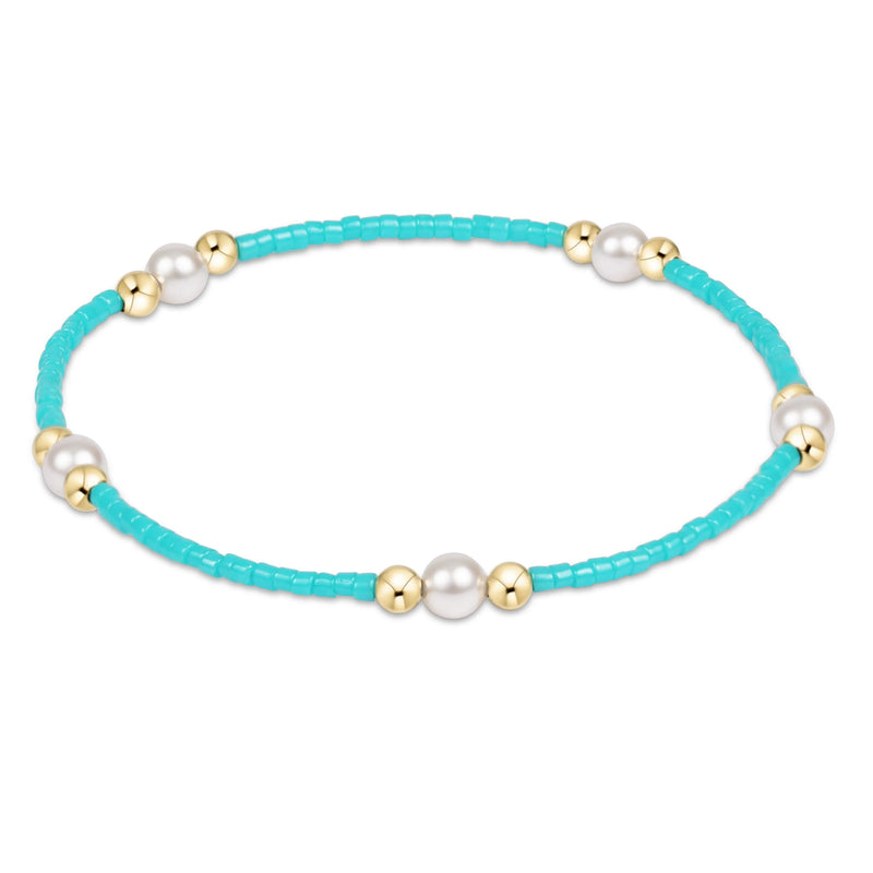 Turquoise beaded bracelet with pearls and gold accents on a white background